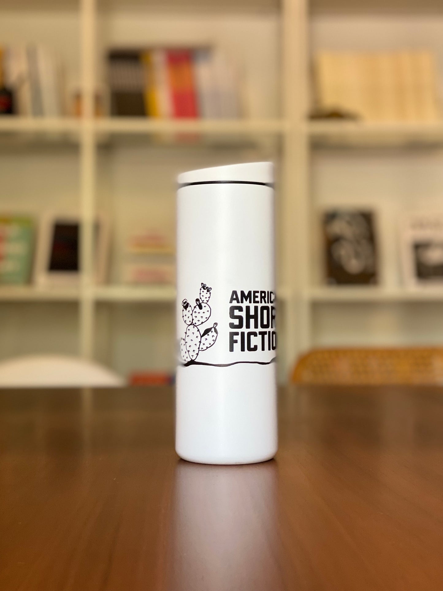 White traveler tumbler with American Short Fiction logo and cactus design.
