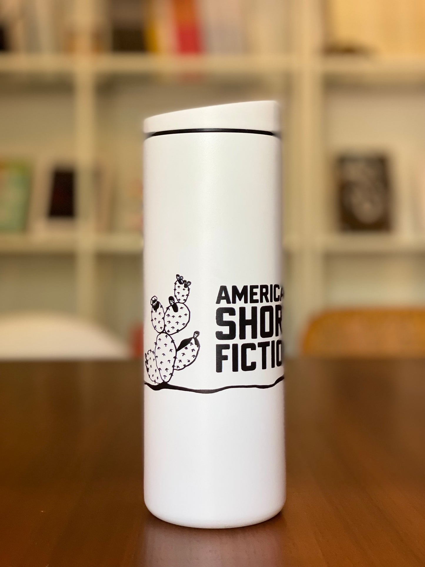 White traveler tumbler with American Short Fiction logo and cactus design.