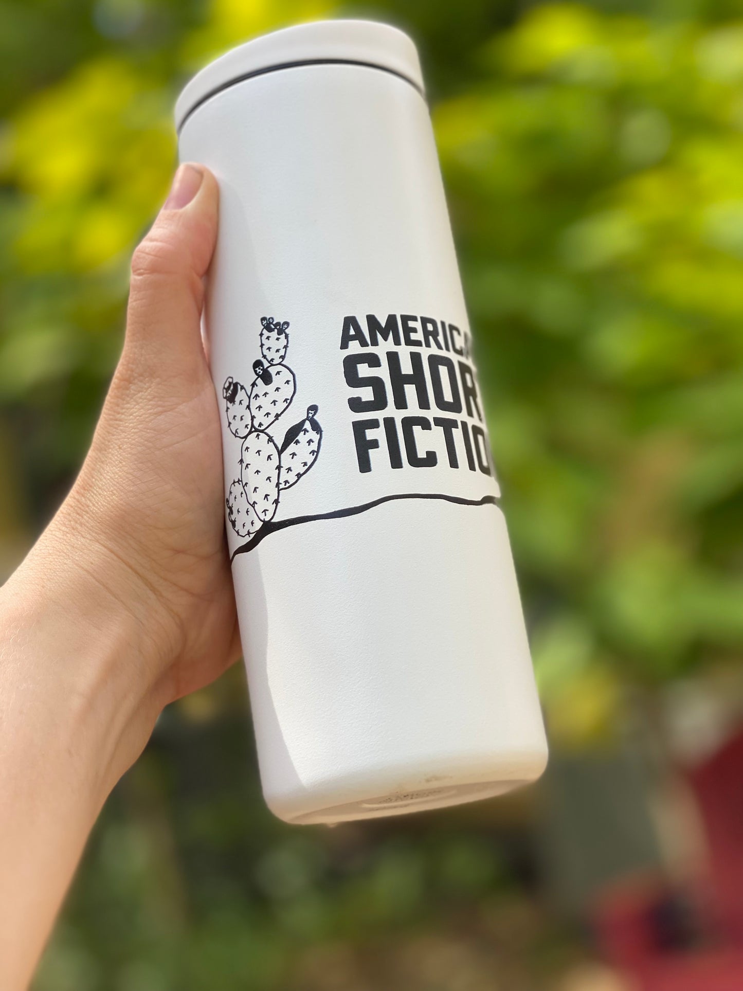 White traveler tumbler with American Short Fiction logo and cactus design.